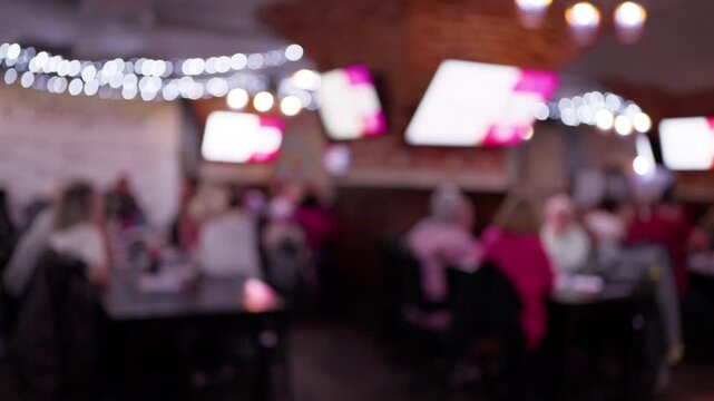 Blurred group socializing inside warm lit banquet hall with string lights and lively evening atmosphere for event use.