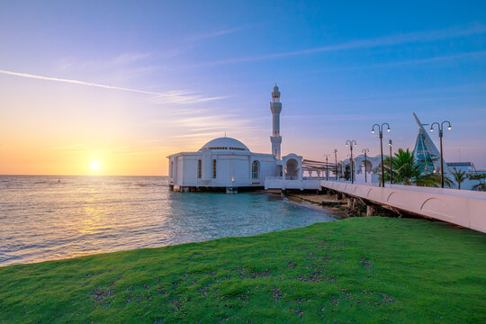 sun goes down on Al Rahmah Mosque on Jeddah Waterfront with JYC Jeddah Yacht Club building, on the Red Sea coast of Saudi Arabia, at sunset