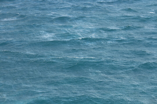 Full frame abstract background texture of blue sea water with choppy waves and white foam on a windy day.