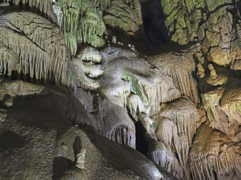 Illuminated flowstone drapes a cave wall, revealing mineral deposits studied in geology to understand how underground cave formations develop.
