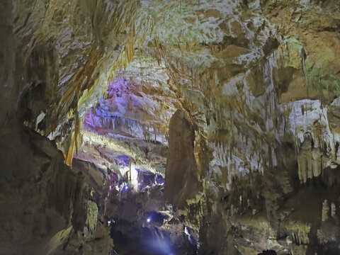 Stalactites crowd an illuminated cave chamber, revealing the mineral deposits studied in geology to understand how underground rock formations grow.
