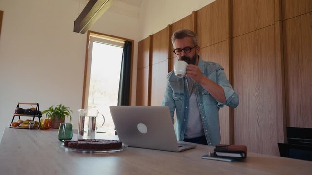 Man working from home office, drinking coffe and working on laptop.