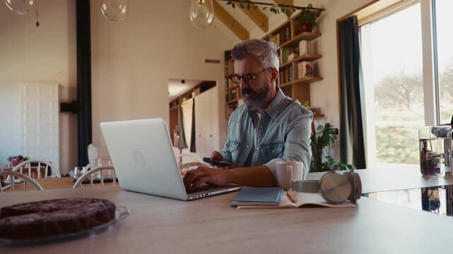 Man working from home office, drinking coffe and working on laptop.