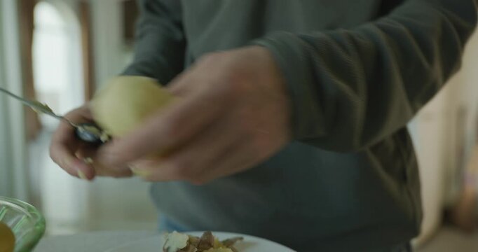 Close-up male hands peel boiled potato with knife. 4K 10-bit