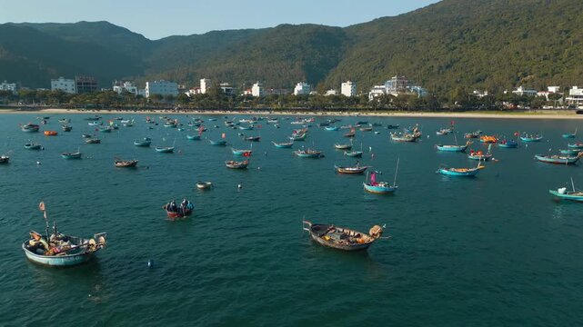 fishing boats and round coracle basket boats floating in sea bay near green mountain coastline in Danang Vietnam, aerial drone view 4k