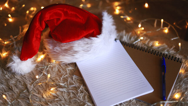 Santa hat and empty blank notepad, Christmas stationery and holiday planning with wish lists and festive letter writing.