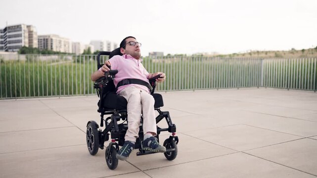 Person with a physical disability, spina bifida, living an independent life. Man moving alone in his powered wheelchair in an urban park