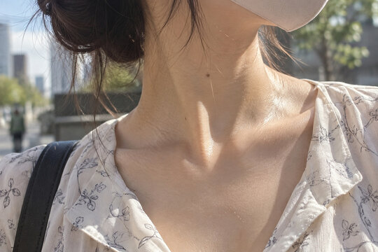 白いマスクと植物柄の襟を着けた女性の首と鎖骨の接写