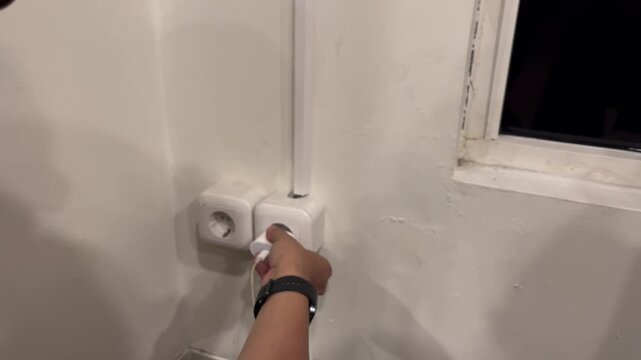 people plugging smartphone charger to electric wall socket