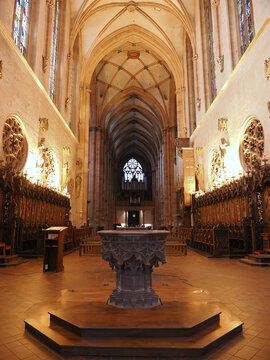Interior view of Saint-Martin Gothic church featuring ribbed vaulting, stone pillars, and ornate baptismal font. Colmar, Alsace, France