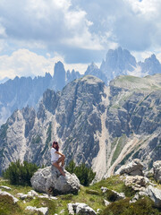 Fototapeta premium Young woman exploring hiking trail in Dolomites near Tre Cime Dolomites Italy