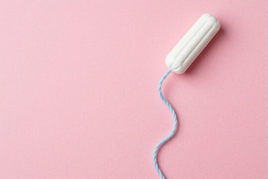 Single white tampon with long blue string on pink background. Minimalist flat lay of feminine hygiene product for menstrual cycle management. Sanitary pad alternative for women health, period care.