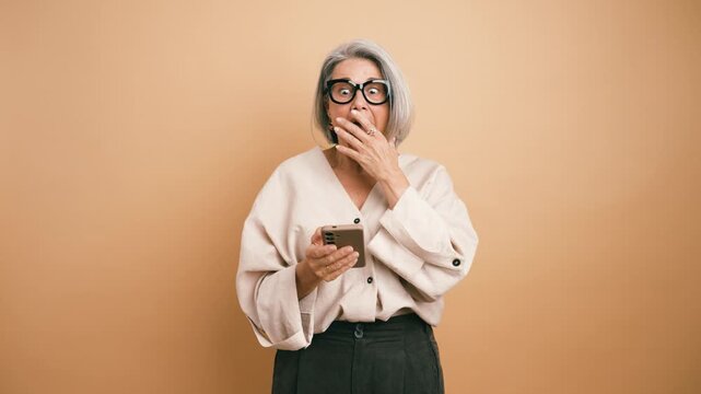 Overjoyed senior woman celebrating a big win on her smartphone. An ecstatic businesswoman shows happiness after receiving good news