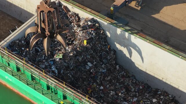 Industrial Claw Crane Lifting Heavy Metal Scrap From a Cargo Ship