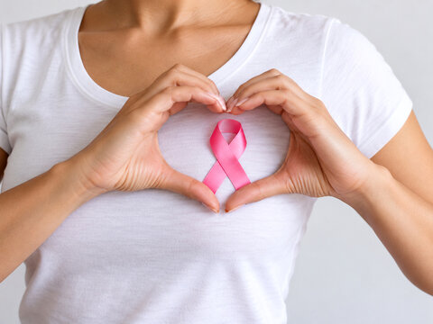 Woman Making Heart Shape with Hands Around Pink Ribbon for Breast Cancer Awareness and Support