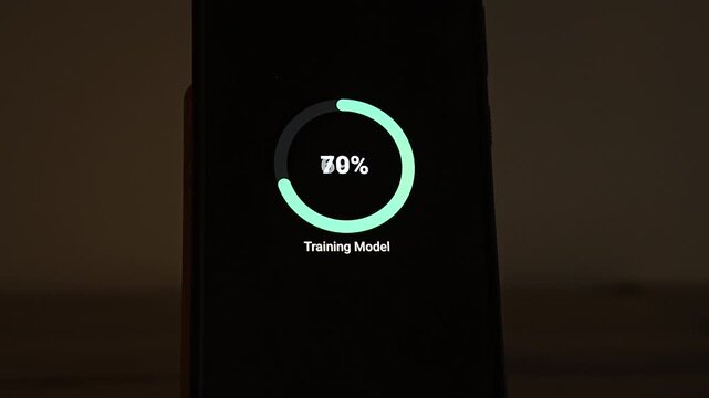 A circular progress ring reaches 50 percent above the label Training Model on a smartphone screen in a dark, warm room. It visualizes machine learning model training, neural network progress, AI deve