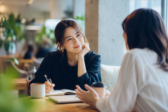 テーブル席でメモを取りながら穏やかに会話を交わす2人のビジネスパーソン