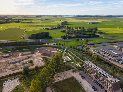 High angle drone shot of A28 highway, green fields, and construction area in Nijkerk