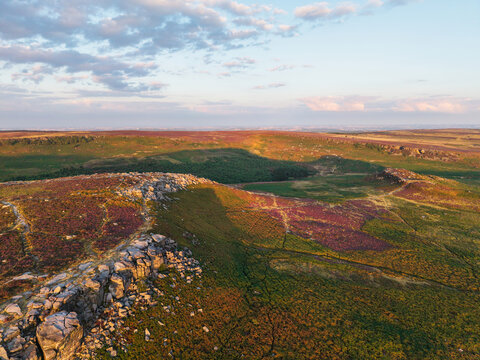 Beautiful drone landscape image view over Burbage South Edge in Peak District during Summer heather sunset
