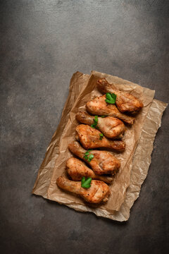 Roasted chicken drumsticks on paper, dark rustic background, top view, flat lay, copy space, vertical