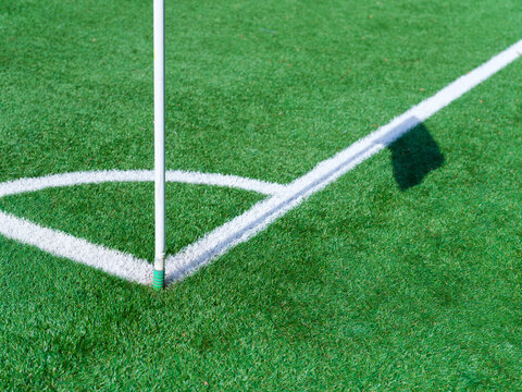Corner marking lines on a green soccer pitch. White boundary lines and corner arc texture on grass field.