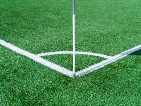 Corner marking lines on a green soccer pitch. White boundary lines and corner arc texture on grass field.