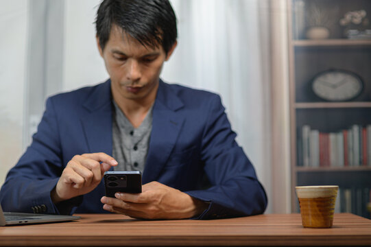 Young Man in Business Suit Using Smartphone at Home Office Desk