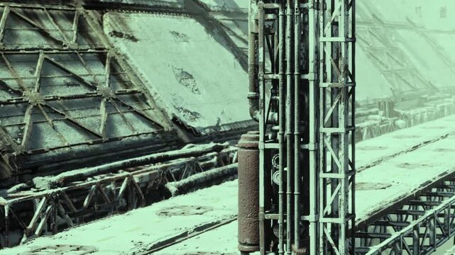 A desolate industrial area lies abandoned, its structures covered in frost. Once active, now it stands silent, lost in time and the harsh grip of winters chill.