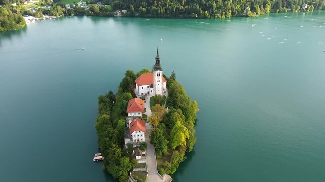 Aerial drone footage of Bled Island during the 2026 Masters rowing regatta on Lake Bled, Slovenia, with the Church of the Assumption, autumn trees and classic double sculls in the background.