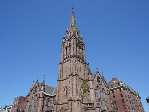 Brownstone Gothic revival church spire against a cloudless sky