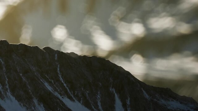 Warm sunlight reflects on the gentle waves, creating sparkles over the water. A majestic mountain rises prominently, showcasing natures beauty in perfect harmony.