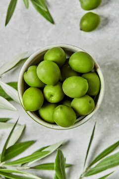 Fresh green olives in ceramic bowl with olive branches