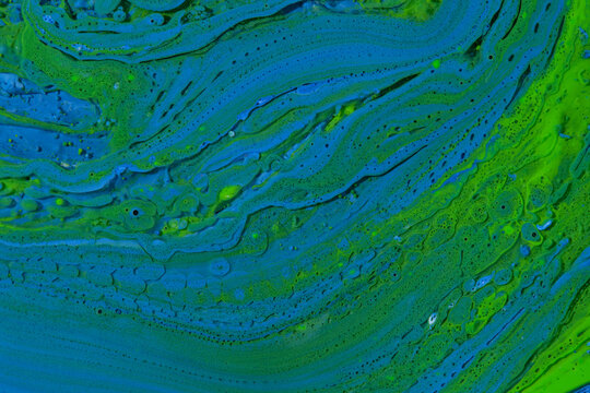 Vibrant green and bright blue fluid art texture with intricate cellular pattern and paint swirls.