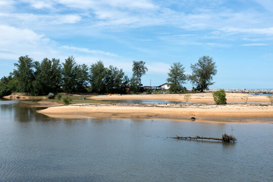 Kuala Kemasik Coastal Lagoon, Terengganu, Malaysia - Peaceful coastal with calm lagoon water, sandy banks, tropical vegetation, coconut palms, and a bright blue sky creating a serene natural setting.