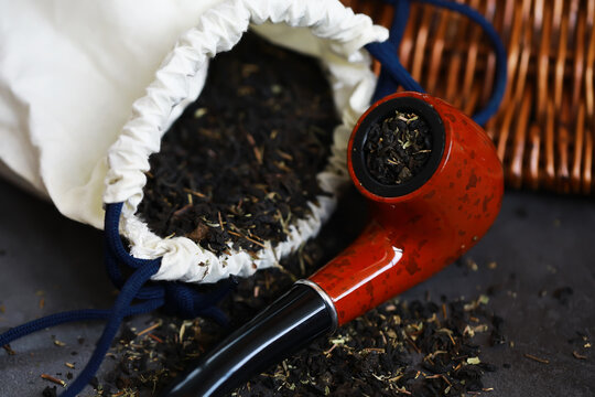 Rustic Pipe with Loose Tobacco in a Drawstring Bag on Dark Surface