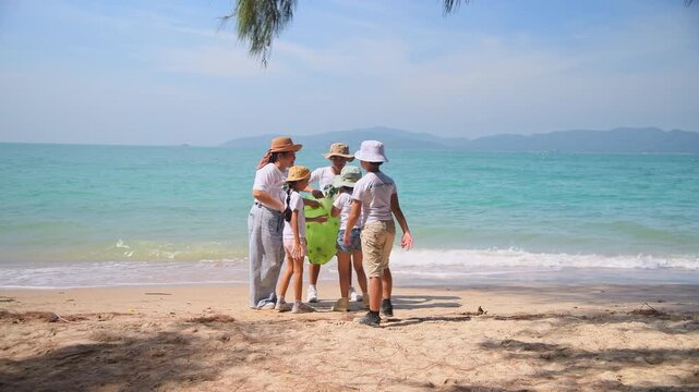 Group of teacher and school children on ecotourist trip  learning show beach take care of environment.