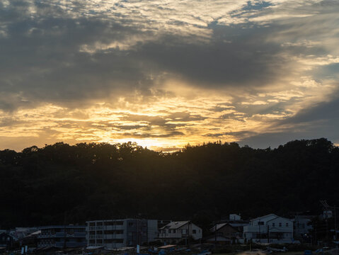 Golden sunset light breaking through clouds over coastal hills and town in Kamakura Japan