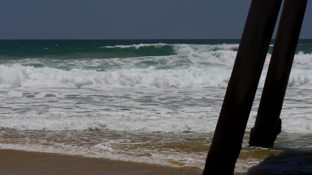 Large waves breaking on an empty beach next to the pier in California