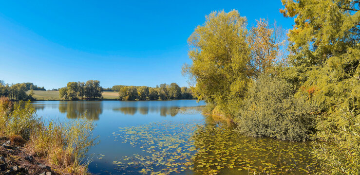 Lake Michelbach in southern Alsace. Water reservoir to the west of the small dike contributing to the filling of Lake , bordered by meadows and lush green vegetation.