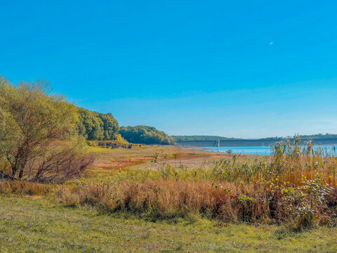 Lake Michelbach in southern Alsace during periods of low water, surrounded by wild nature of the nature reserve (Aspach-Michelbach), reedbeds and sandbanks, with a view to the east of the main dike

