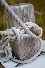 White rope is tied around a weathered wooden post aboard a boat on Lewis and Harris, Outer Hebrides, Scotland. © George