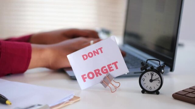 The words "DON'T FORGET" and a small alarm clock, set against a background of hands typing on a keyboard. A general business image used to remind someone of something important.