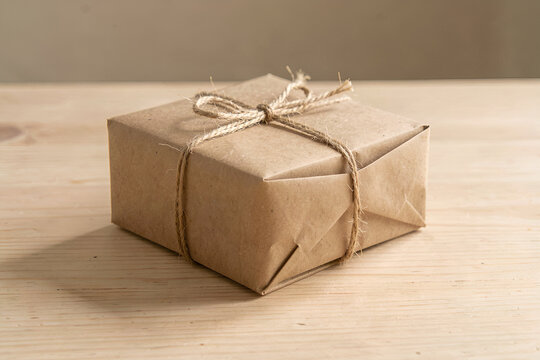 Small unbleached cardboard parcel tied with twine on a wooden tabletop