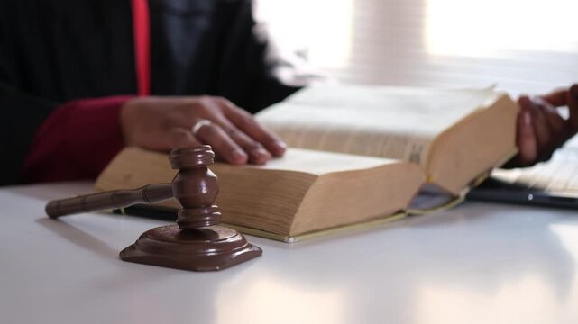 A judge opens a large book to consult legal references&mdash;encompassing legal concepts, jurisprudence, and legal education. A lawyer or advocate is seen reading legal texts, documents, and statutes. Close
