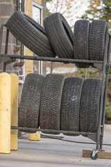 Stack of new tires on metal rack beside garage entrance © primestockphotograpy