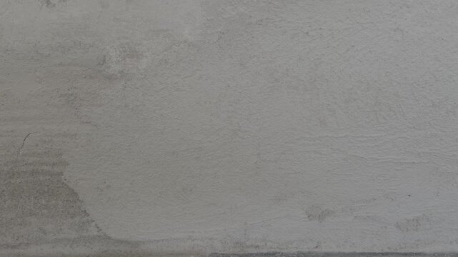 Plaster wall reveals fine cracks and uneven texture during a close pan