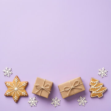Festive holiday arrangement with gifts gingerbread and paper snowflakes on a lilac background