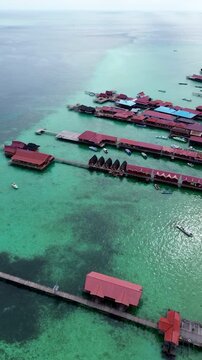 Vertical aerial view overwater cottages resort in turquoise water Derawan Island
