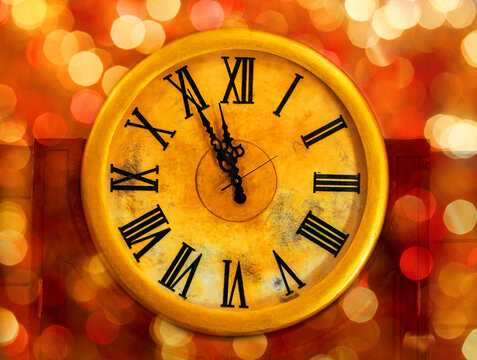 An antique golden clock with ornate black Roman numerals and hands against glowing red and orange bokeh background, New Year, time passing, nostalgia, vintage elegance, countdown anticipation