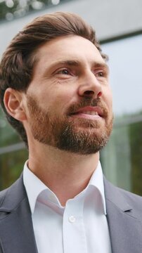 Close-up portrait of a smiling Caucasian adult man outdoors, looking around and observing his surroundings. Positive and relaxed male enjoying a pleasant day outside with a natural and authentic